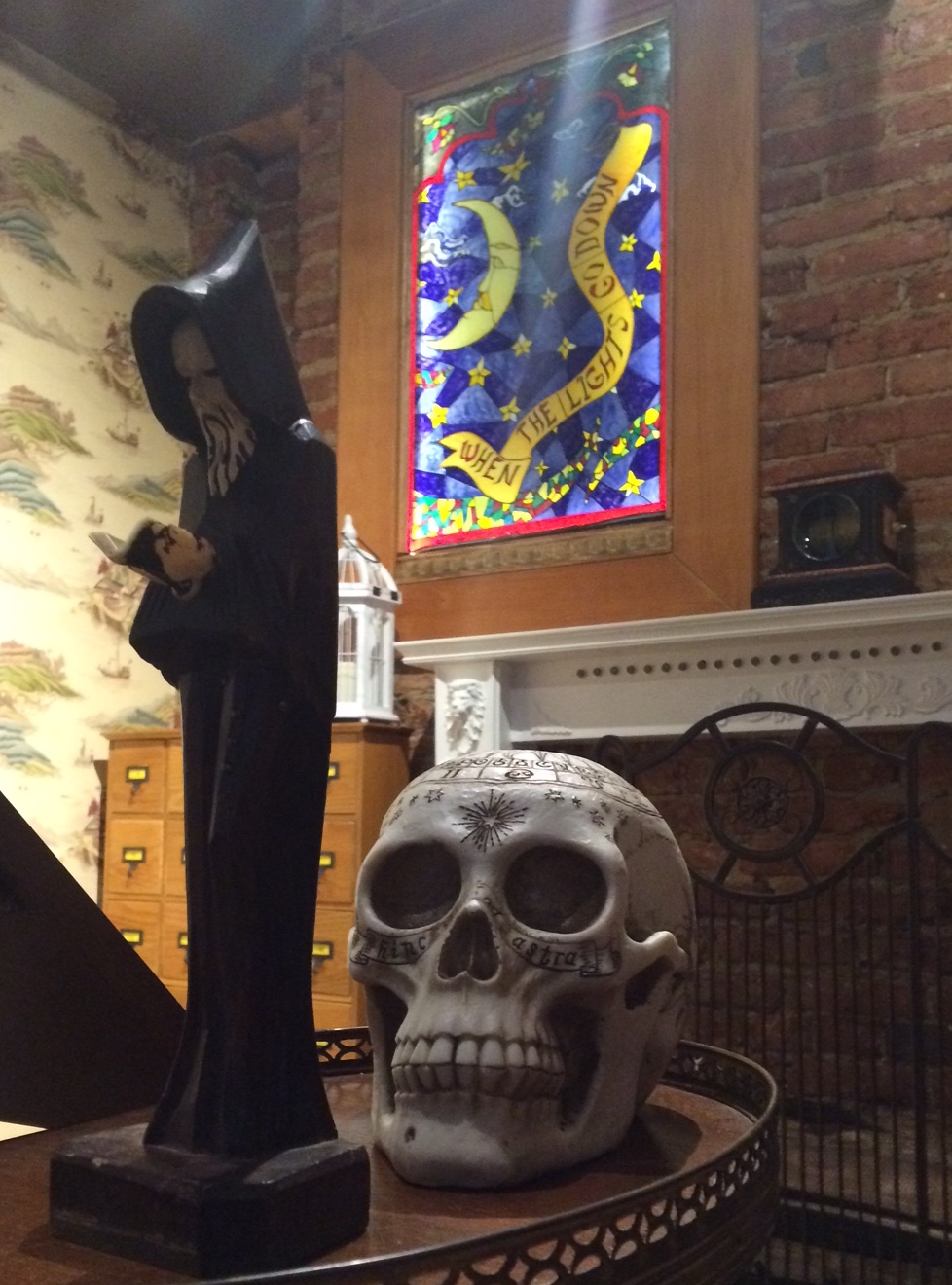 In-game photo of a wizard statue, an intricately engraved human skull, and a stainglass window in the background.