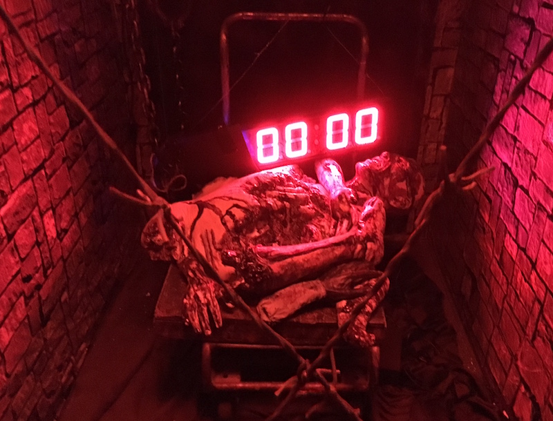 In-game: A red digital countdown clock illuminates a dead body