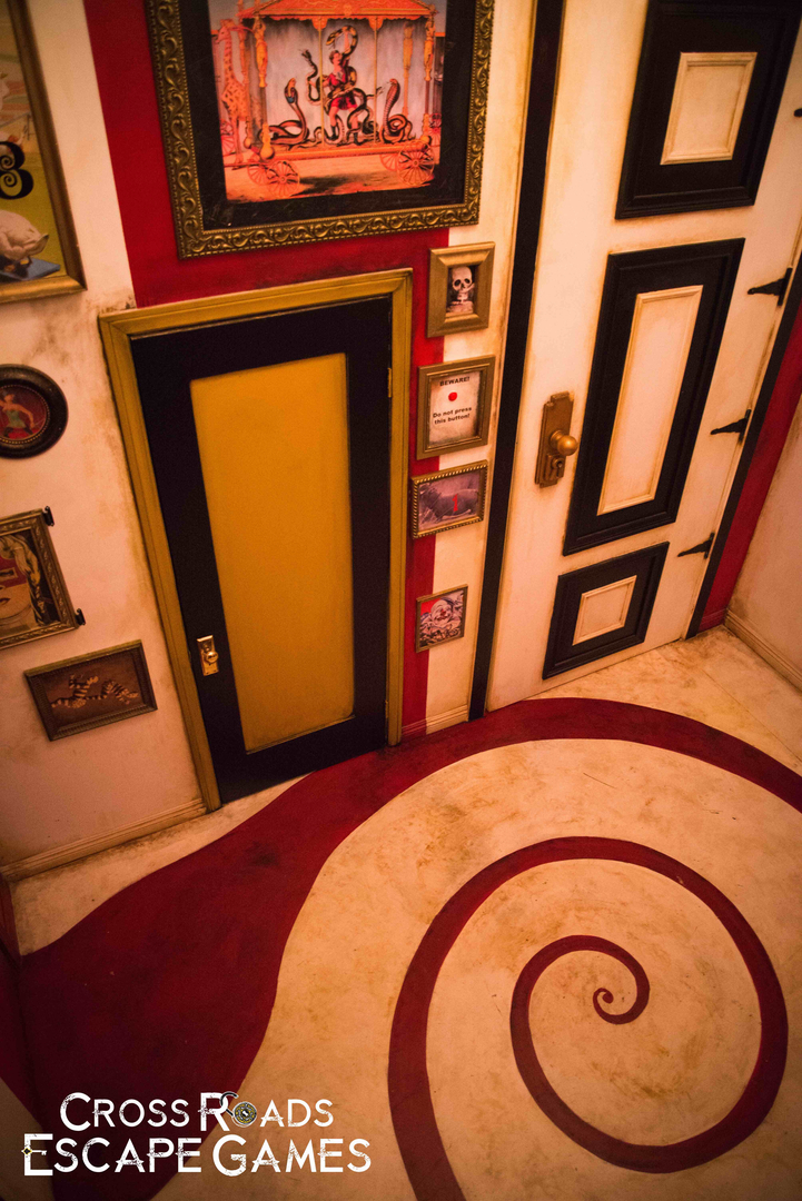 In-game, a colorful room with large and small doors, images all over the wall,s and a spiral pattern on the floor.