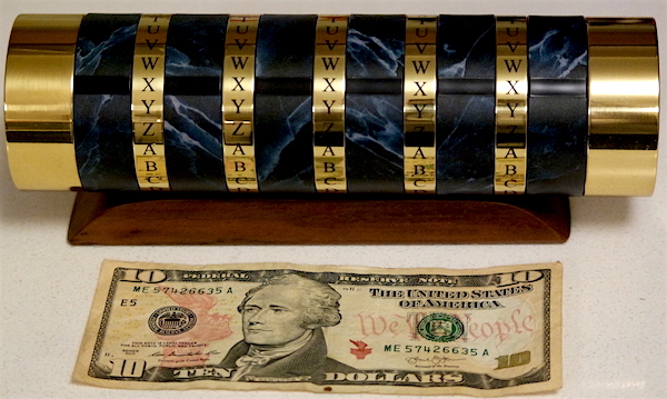 Locked cryptex beside a $10 bill for size reference, it's a few inches longer and a little wider.