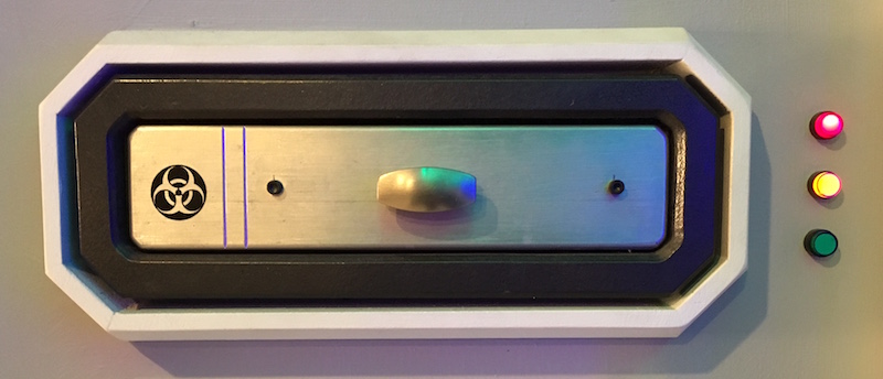 In-game, a piece of lab equipment with a biohazard symbol and three lights: red, yellow, and green.