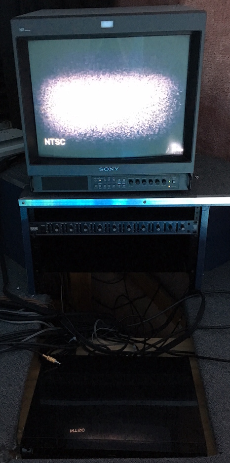 An old CRT TV displaying static. A mess of wires rests underneath it.