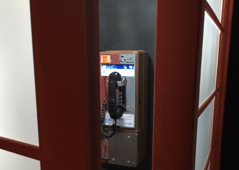 Interior of the phone booth: A pay phone is mounted to the wall.