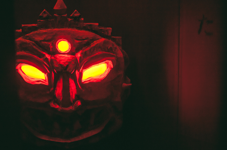 In-game: A red glowing demon's face in the shadows.