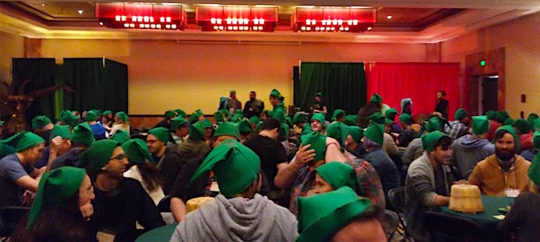 In-game: A ballroom full of seated players all wearing green Link elf hats.