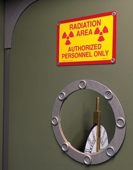 In-game: A submarine door with a radiation warning. Through the porthole is a depth controller.