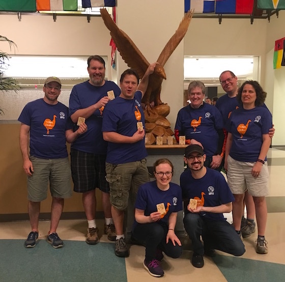 Team EMBU victory photo in the Auburn University Student Center. The team is gathered around the war eagle holding trophies.