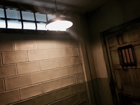 In game: A heavily weather concrete wall with a metal door. A light hangs about them.