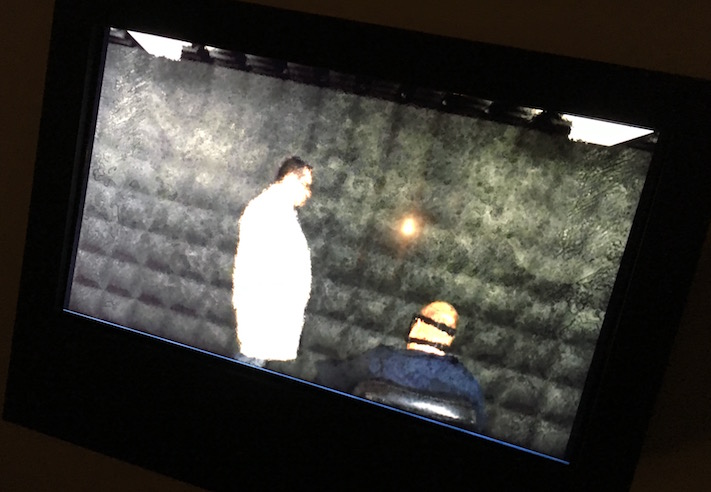 In-game: a TV depicting a doctor speaking with a restrained patient in a padded cell.