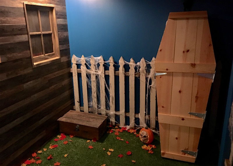 In-game: The exterior of the haunted house featuring a coffin, locked box, and log cabin.