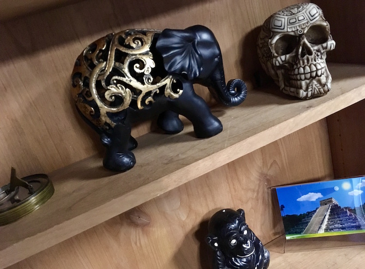 In-game: A shelf with assorted artifacts and an image of a Mayan temple with the moon eclipsing the sun. 