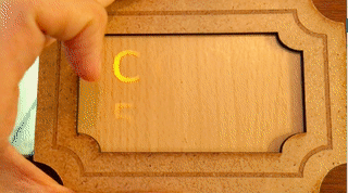 Animation of the Illuminating Wood puzzle with a light behind it. A hand moves it and the "CODE 5723" illuminates as the light passes by.