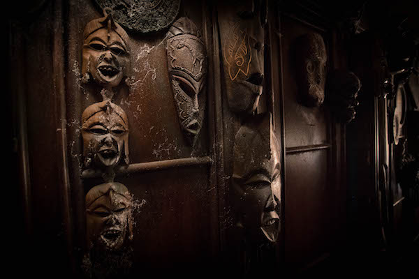 In-game: A wall covered in cobwebbed tribal masks.