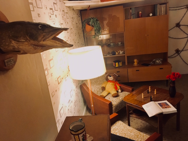 In-game: A drab 1980s living room in East Berlin. A stuffed fish named Erich hangs on the wall. 