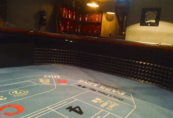 In-game: shot from within a craps table, the casino's bar lit in the background. 