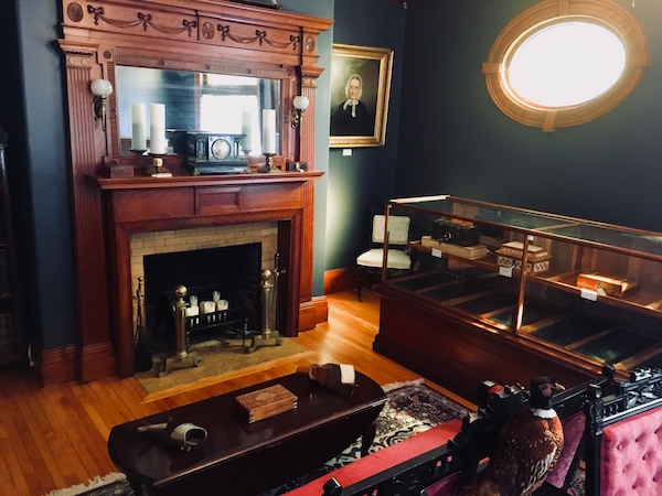 In-game: A loung in an old mansion. There's a beautiful fireplace, and a cabinet filled with locked boxes. 