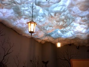 A ceiling of cotton clouds with old lanterns hanging from it. The clouds are illuminated like lightning.