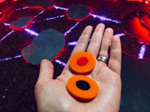 In-game: A hand holding two tokens, one with a red dot, the other a black dot.