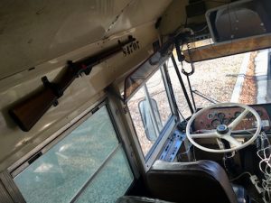 In-game: Overhead of the driver's seat. There is a rifle mounted to the wall, and a lot of extra wiring.