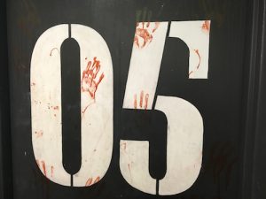 In-game: the number 05 painted to the wall and covered in bloody handprints.
