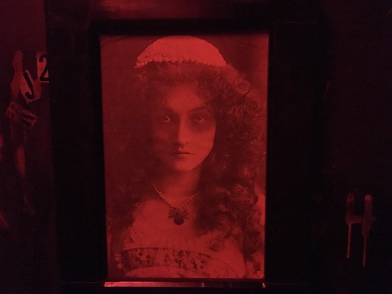 In-game: a hanging red and black portrait of a woman.