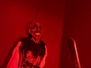 In-game: A creepy party-store clown hanging from the wall by a string holding a large knife.