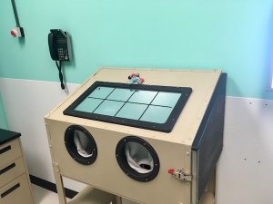 In-game: A clean box with large arm holes in a blue and white science lab.