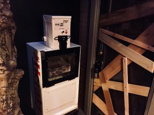 In-game: a newspaper vending machine beside a boarded up business' door.