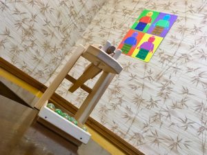 In-game: a wooden toy with marbles in it in a room with wallpaper from the 70s.