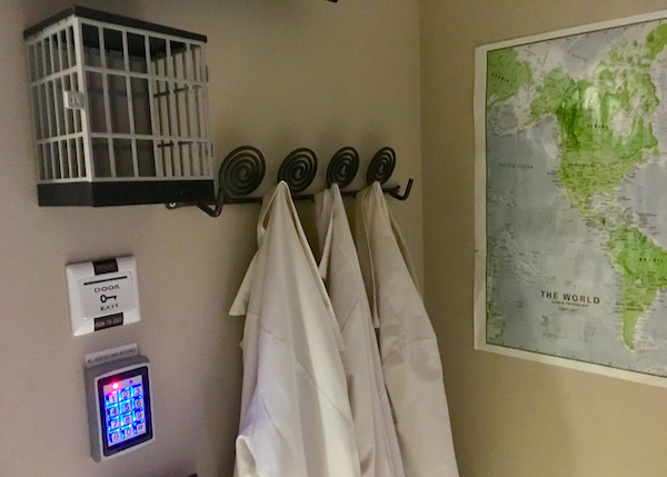In-game: Lab coats hanging on a wall beside a digital keypad and a world map.