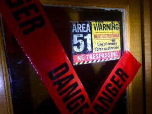In-game: a cabinet marked with red danger tape and labeled, "Area 51 Restricted Area."