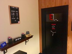 In-game: A bank safe beside a paperwork table.