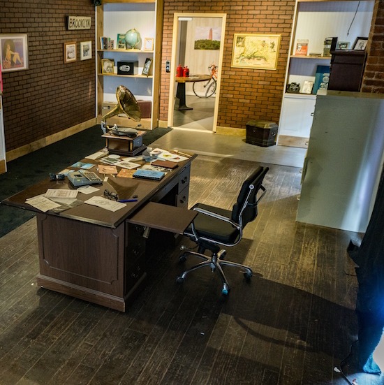 In-game: An old office with a desk covered in papers an old gramophone.