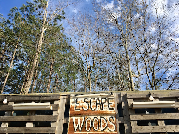The rusty hand painted Escape Woods sign.