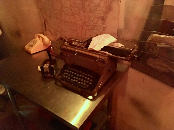 In-game: An old broken typewriter on a desk beside a Brownie camera, and rotary phone.