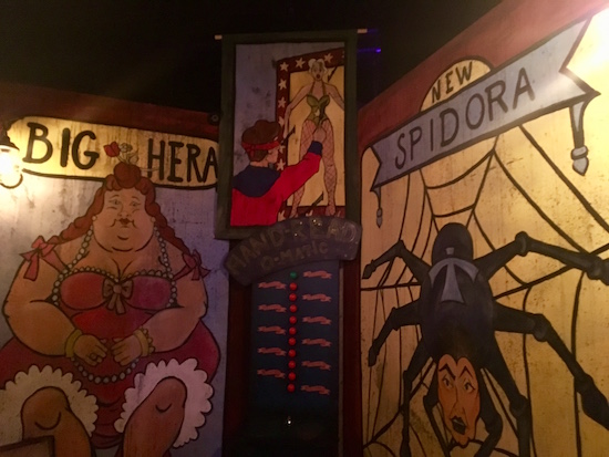 In-game: Advertisements for different freakshow performances including Big Hera and New Spidora.