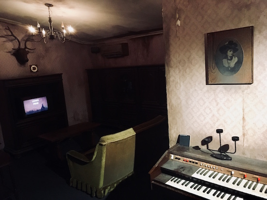 In-game: A grim and rundown living room with an old dusty synthesizer.