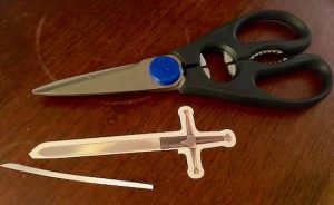 The Forbidden Castle's sword with a sliver of card stock cut off beside a pair of scissors.