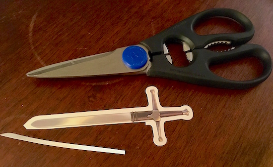 The Forbidden Castle's sword with a sliver of card stock cut off beside a pair of scissors.