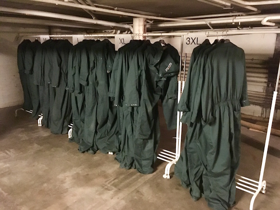A clothing rack with hunter green jumpsuits.