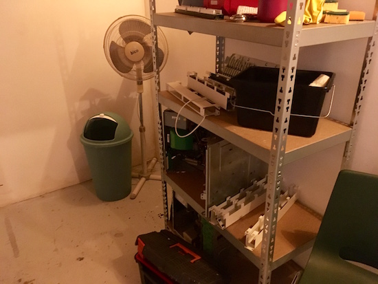 In game: a storage area with shelving covered in computer and cleaning equipment.