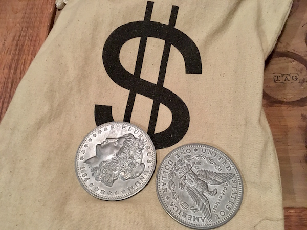 In-game: Close-up of a money back and large silver dollars.