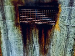 In-game: a closeup of a cell door with a rusty grate.