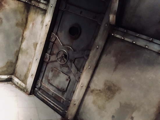 In-game: the weathered metal walls and a large sealed door.
