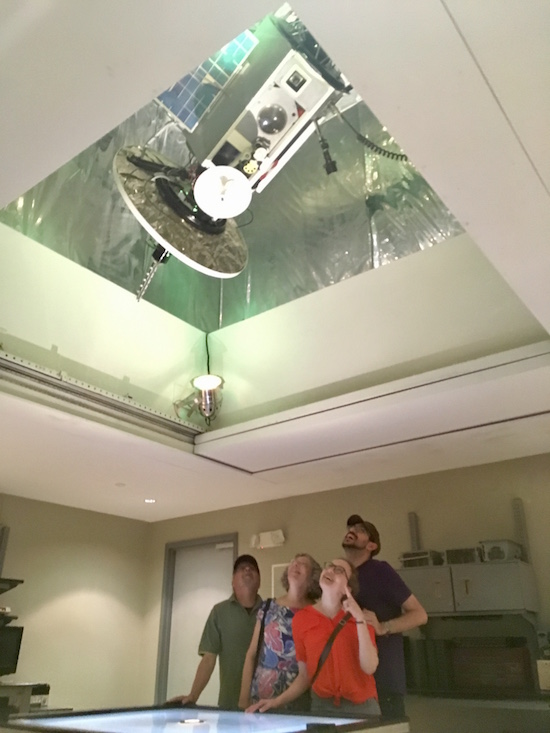 In-game: Lisa, David, and Lisa's parents looking up at a spy satellite.