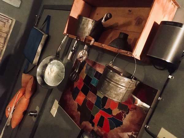 A collection of pots hanging from a cabinet in the a rustic cabin.