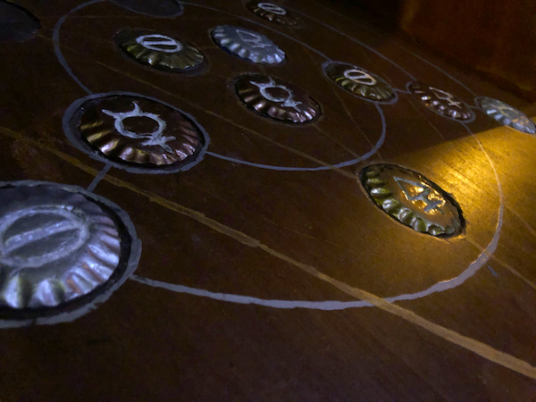 In-game: A wooden table with strange medallions mounted to it.