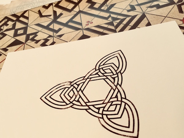 In-game: A card with a complex knot pattern, on top of an unusual paper maze of some sort.