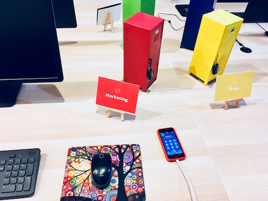 In-game: a close up of the marketing desk with a mouse, keyboard, and a locked iPhone.
