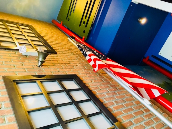 In-game: The exterior of the school building with a PA and American flag.